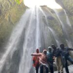 Un gruppo di persone felici sotto la cascata di Gljúfrabúi