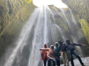 Un gruppo di persone felici sotto la cascata di Gljúfrabúi