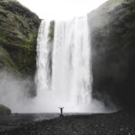 Una persona sola davanti all'imponente cascata Skogafoss