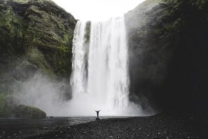 Una persona sola davanti all'imponente cascata Skogafoss